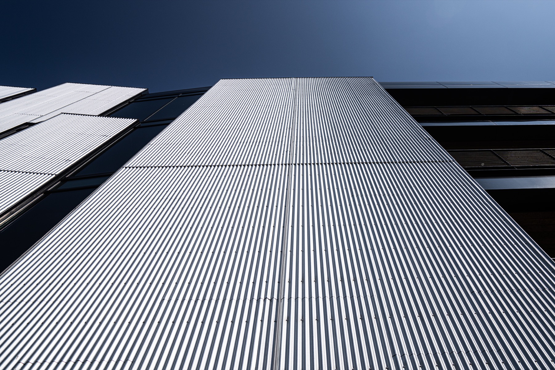 Looking up along the textured white building facade toward blue sky